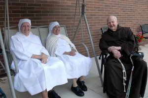 Fr. Cyprian Berens, OFM, sits with two nuns of the Little Sisters of the Poor