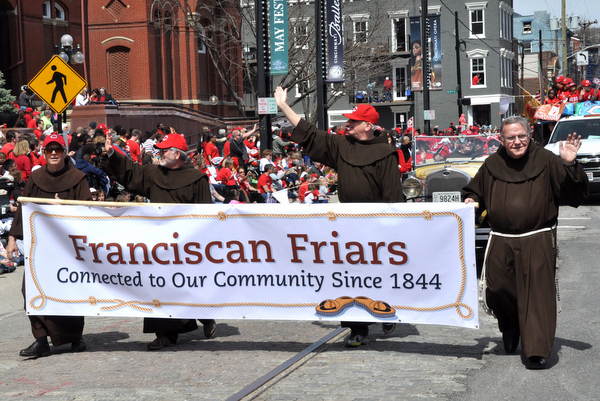 Br. Kenn Beetz, OFM, Fr. Jeff Scheeler, OFM, Fr. Al Hirt, OFM, and Br. Gene Mayer, OFM, take turns carrying the banner in the Reds Findlay Market Opening Day Parade.