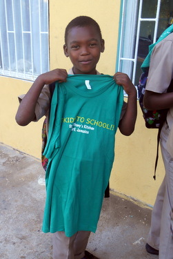 A student proudly holds a 'Get Kids To School' t-shirt